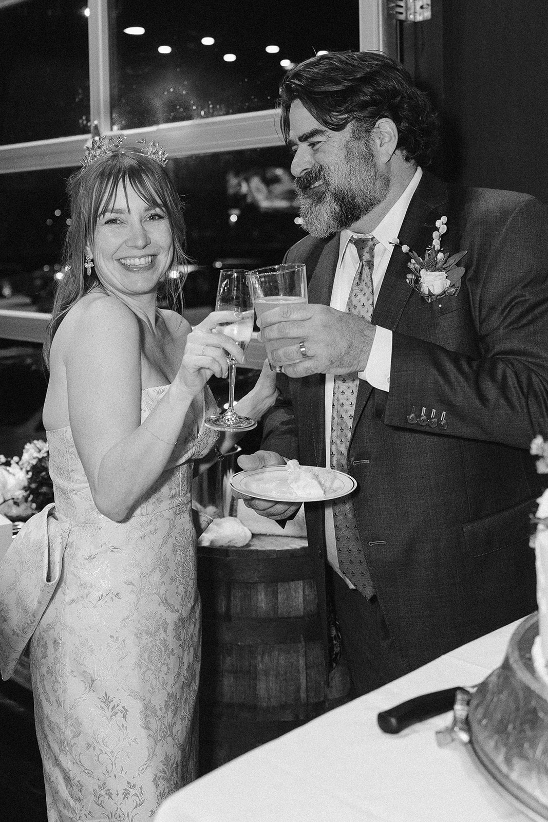 Black-and-white photograph of Katie and Jeff smiling together and raising champagne glasses at their wedding reception.